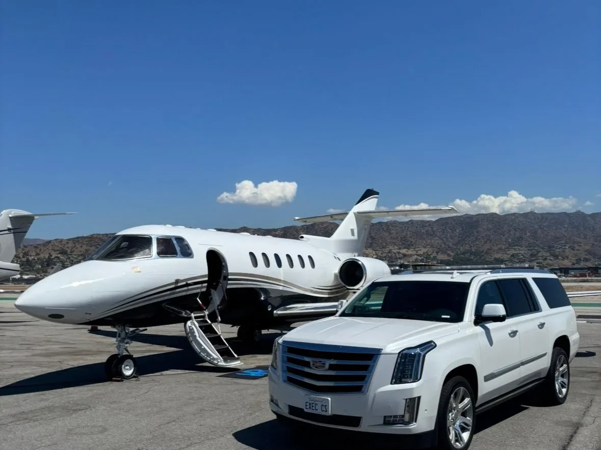 White luxury SUV from Executive Car Service parked beside a private jet on the tarmac, EXEC CS plate visible