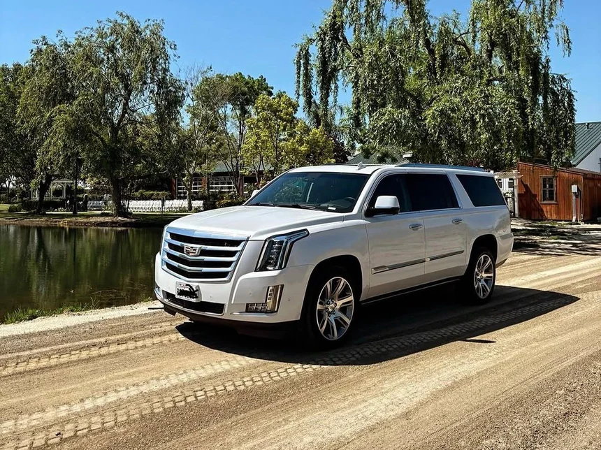 White luxury SUV at a wedding venue with the ceremony chairs set out by the pond